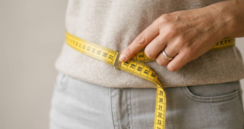 Taillenumfang wird mit einem Maßband gemessen als Selbsttest für hormonell bedingtes Bauchfett